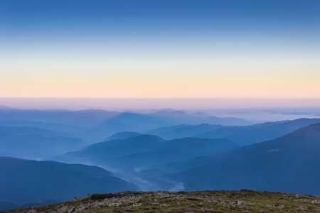 View from the top to the many mountain ranges of the Carpathians before dawn.の写真素材