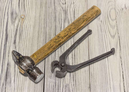 Old hammer and pliers for pulling out nails on the surface from an old blackened wooden planks.の写真素材