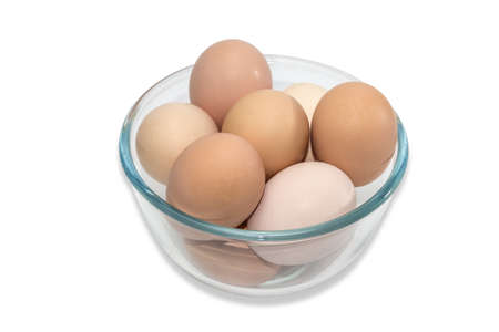 Transparent glass bowl with light brown chicken eggs on a light . Isolation.の写真素材