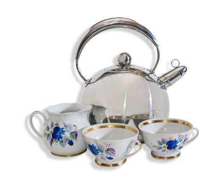 Kettle in stainless steel with a whistle porcellaneous jug and cups on a light . Isolation.
