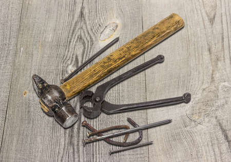 Old hammer pliers for pulling out nails and several different nails on the surface from an old blackened wooden planks.の写真素材