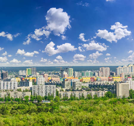 Residential quarters of the modern city with high-rise apartment buildings, houses under construction, park in the foreground against the sky with cloudsの写真素材