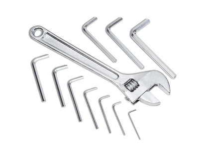 Silvery adjustable wrench and set of silvery allen keys different sizes on a light background....