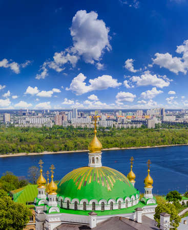 The dome of a temple against the residential neighborhoods of the city and the sky with clouds....