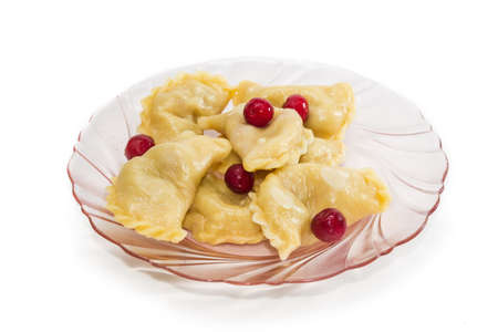 Ukrainian varenyky (dumplings) filled with sour cherry and cherries separately on a dish of pink...