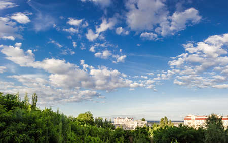 Sky with clouds with trees in the foreground and the buildings in the background summer in afternoon