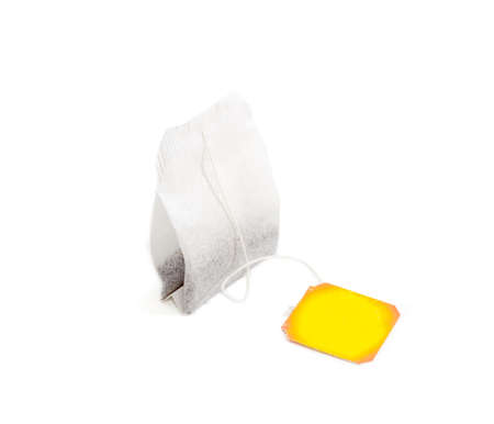 One tea bag made of filter paper with black tea and yellow paper label on a light background closeup. Isolation.の写真素材