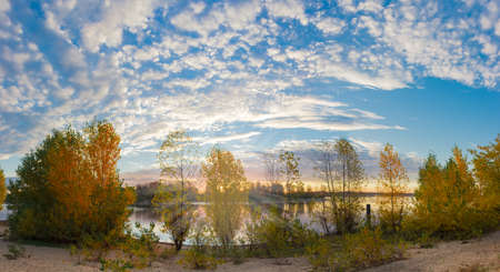 Panorama of the river during the sunrise autumn. Sandy shore of the river and trees with yellow...
