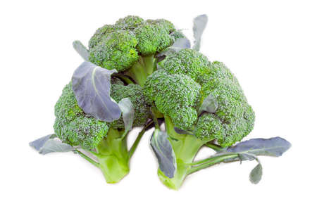 Three head of fresh purple broccoli with thick stalks and leaves on a light background.