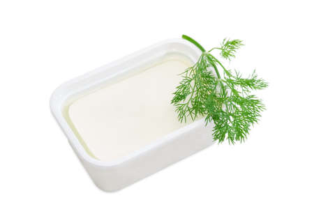 Rectangular container of feta cheese in a brine and a branch of a dill on a light backgroundの写真素材