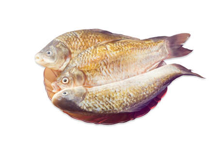 Three carps with peeled scales on red glass dish and prepared for cooking on a light background. Isolation.の写真素材