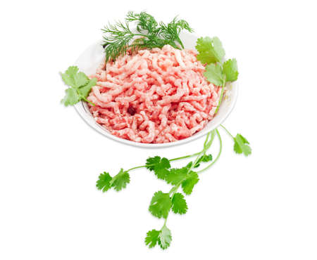 Ground meat, made from a pork with branches of a coriander and dill in bowl on a light background. Isolation.の写真素材