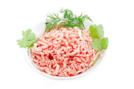 Ground meat, made from a pork with branches of a coriander and dill in bowl on a light background. Isolation.の写真素材