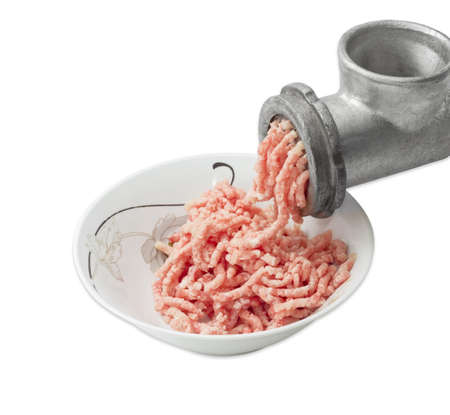 Ground meat, made from a pork in bowl and fragment of a old hand powered meat grinder during grinding of meat on a light background. Isolation.の写真素材