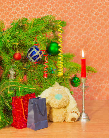 Fragment of a decorated Christmas trees, candle in a candlestick, soft  toy and Christmas Giftの写真素材