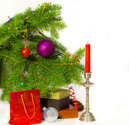 Branch of a decorated Christmas trees, candle in a candlestick and Christmas Gifts on a light backgroundの写真素材