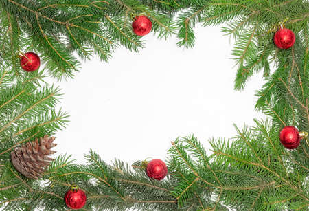 Fir branches, cone and several Christmas ornaments, laid out on the perimeter, as a frame with empty center part on a light backgroundの写真素材