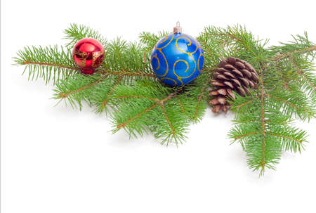 Branch of a fir tree with cone and Christmas ornaments on a light backgroundの写真素材