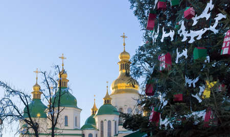Fragment of decorated public Christmas tree on the background of a sky and cathedral domesの写真素材