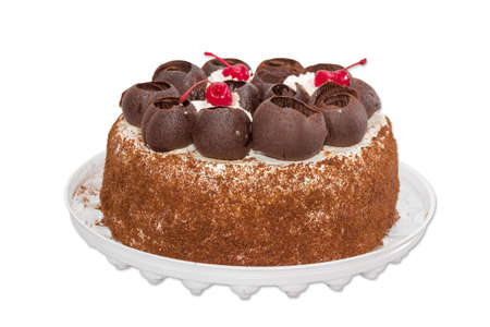 Round sponge cake, decorated with chocolate, whipped cream and frozen cherries on a light background. Isolationの写真素材