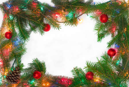 Fir branches, several Christmas ornaments and Christmas mini lights, laid out on the perimeter, as a frame with empty center part on a light backgroundの写真素材