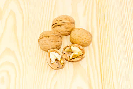 Three ripe whole walnuts in shell and one walnut splited in half closeup on a wooden surfaceの写真素材