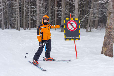Young skier near a warning sign on the background of spruce forestの写真素材