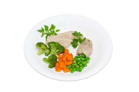 Boiled meat with boiled green peas, broccoli, carrot and sprigs of parsley on a white plate on a light backgroundの写真素材