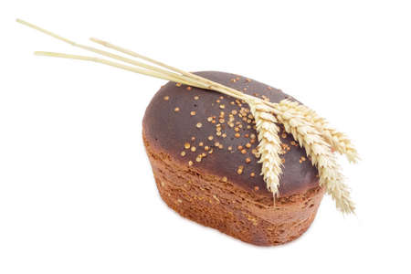 Whole loaf of brown bread with coriander and three ears of wheat closeup on a light background