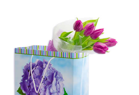 Bouquet of dark red tulips in a paper bag for gifts on a light background closeupの写真素材