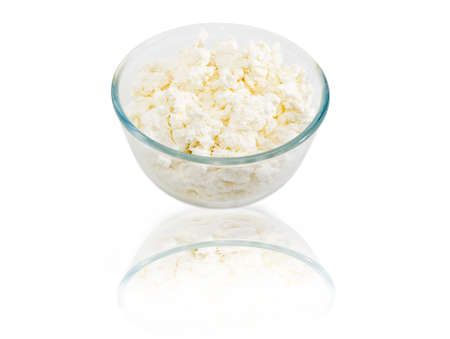 Transparent glass bowl with fresh cottage cheese on a light backgroundの写真素材