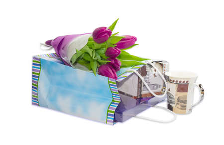 Bouquet of dark red tulips on a paper bag with gifts and coffee cup on a light background closeupの写真素材