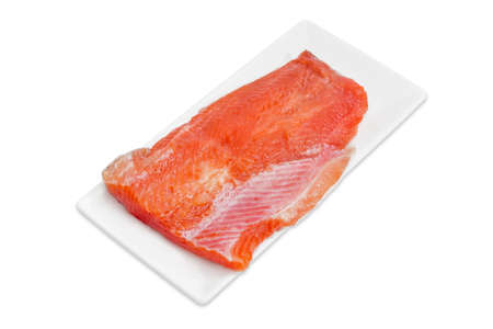 Piece of fresh uncooked fillet of rainbow trout on a rectangular white plate on a light background