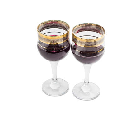 Red wine in two wine glasses with golden ornament on a light backgroundの写真素材