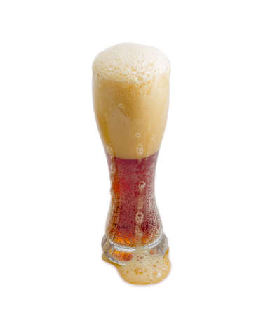 Beer glass with dark beer and a large head of foam, flowing on the beer glass on a light backgroundの写真素材
