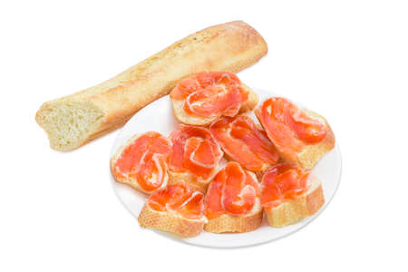 Sandwiches made with pieces of baguette, butter and slices of a salted rainbow trout on white dish and a piece of baguette on a light backgroundの写真素材