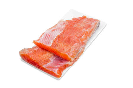 Two pieces of fresh uncooked fillet of rainbow trout on a rectangular white plate on a light backgroundの写真素材