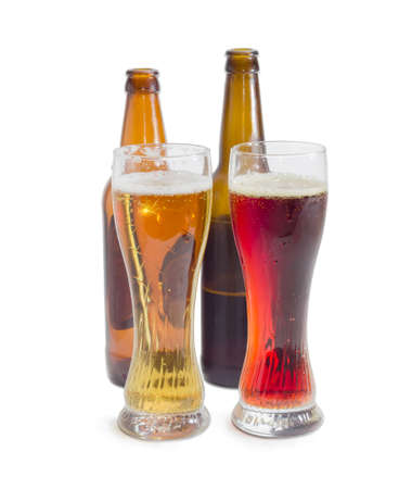 Two beer glasses with lager beer and dark beer against of beer bottles on a light backgroundの写真素材