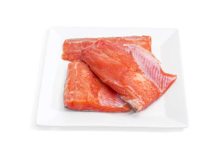 Several pieces of fresh uncooked fillet of rainbow trout on a square dish on a light background closeupの写真素材