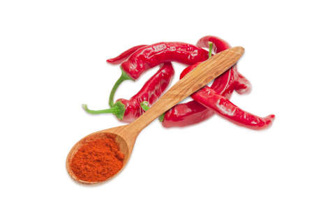 ?hili powder in a wooden spoon and several fresh red peppers chili on a light backgroundの写真素材