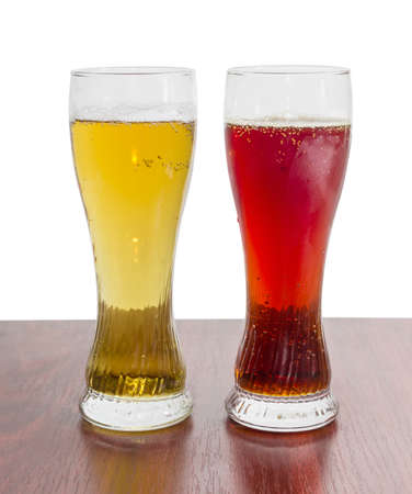 Two beer glasses with lager beer and dark beer on a wooden table on a light backgroundの写真素材