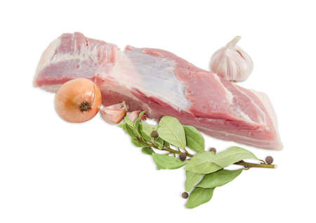 Piece of  a fresh uncooked pork belly with layers of muscle and fats, onion, garlic, Branch with dried bay leaves and a few peas allspice on a light backgroundの写真素材