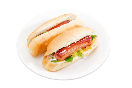 Two hot dog with grilled frankfurter, cheese and mayonnaise in bun with sesame seeds on a white dish on a light background. Isolation.の写真素材
