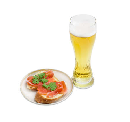 Beer glass with lager beer and two sandwiches made with a salted trout on saucer on a light backgroundの写真素材