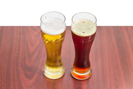 Two beer glasses with lager beer and dark beer on a wooden table on a light backgroundの写真素材