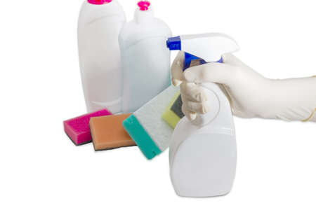 Hand in household rubber glove with spray bottle of cleaning agent on the background of several synthetic cleaning sponges and bottles of cleaning agentの写真素材