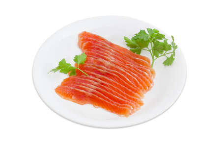 Sliced fillet of salted rainbow trout and a sprigs of parsley on a white dish on a light backgroundの写真素材