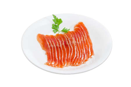 Sliced fillet of salted rainbow trout and a sprig of parsley on a white dish on a light backgroundの写真素材