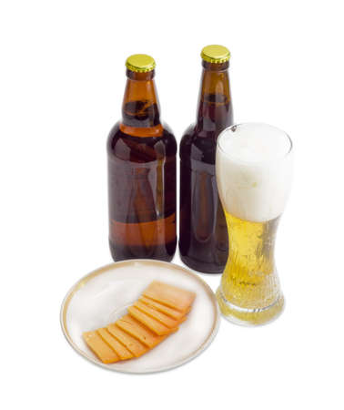 Beer glass with lager beer, two bottles beer and several thin slices of hard cheese on saucer on a light backgroundの写真素材