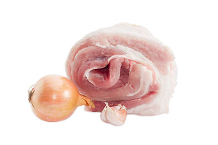 Roll of a fresh uncooked pork belly with layers of muscle and fats, bulb onion and two garlic cloves on a light backgroundの写真素材